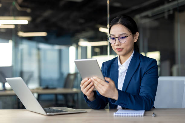 istock Asian businesswoman using tablet in modern office environment, focused on digital work tasks 2174673407