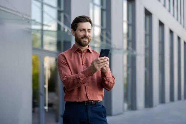 istock Confident businessman using smartphone outdoors in urban environment with modern office buildings in background 2174673661