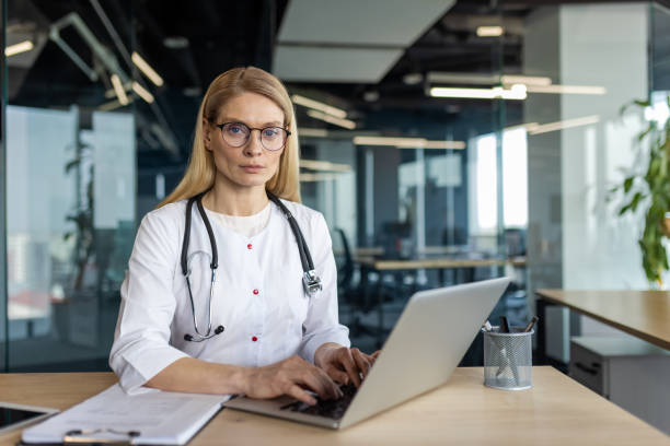 istock Confident female doctor wearing glasses working on laptop in modern office environment 2174677724