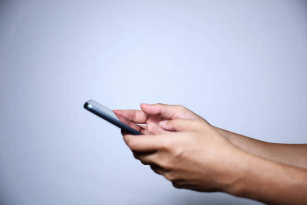 istock Closeup of hand holding or using smartphone on blue background. 2174677816