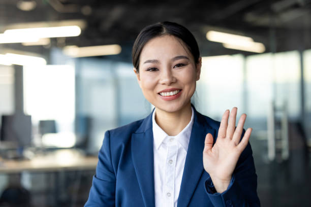 istock Professional woman smiling and waving during a video call in a modern office setting 2174677830