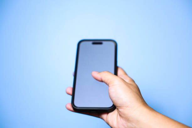 istock Closeup of hand holding or using smartphone on blue background. 2174678069