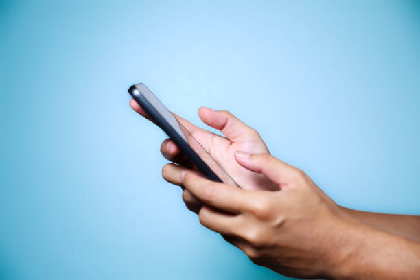 istock Closeup of hand holding or using smartphone on blue background. 2174678280