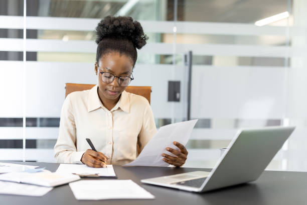 istock Focused African American businesswoman analyzing documents and taking notes at office desk 2174678776