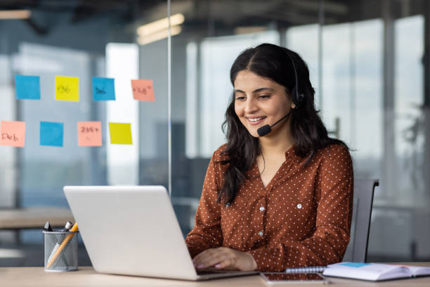istock Young beautiful online support worker at workplace, hispanic woman using headset phone for video call, business woman typing on computer keyboard smiling 2174679219