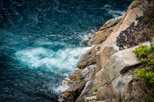A magnificent cliff that majestically overlooks the vast ocean, with waves crashing powerfully against the rugged rocks below