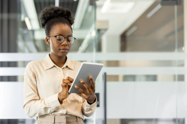 istock Young african american woman using tablet at modern office, focused on work and productivity in professional environment 2174682002