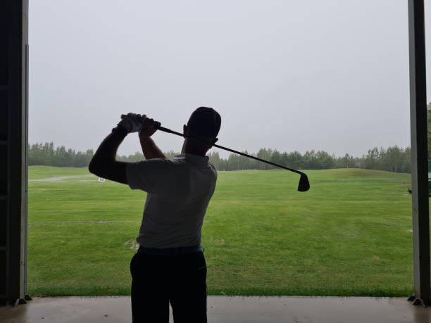 istock Golfer practicing swings at a driving range during a rainy day with overcast skies and lush green grass in the background 2174683004