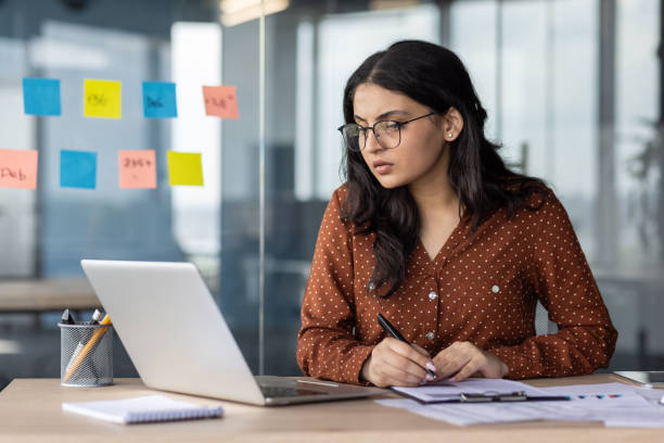 istock Serious thinking and concentrated focused business woman behind paper work inside office. An employee of the company compares the data of the report with documents, an accountant, auditor at work 2174683234