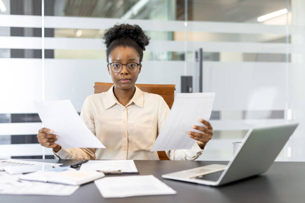 istock Focused African American businesswoman analyzing documents at her desk in modern office environment with laptop 2174685479