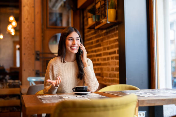 istock Young woman talking on the phone sitting in cafeteria 2174685606