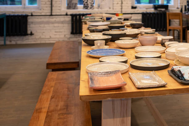 Handcrafted ceramic dishes displayed on a wooden table in a cozy, rustic workshop environment