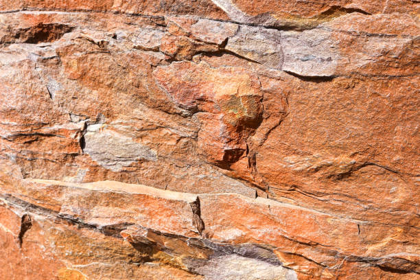 Orange Rock, sandstone background, graphic resource, textured and layered rock face in high detail. Showing years of weathering and damage with many jagged edges. Multiple colours from Orange to grey