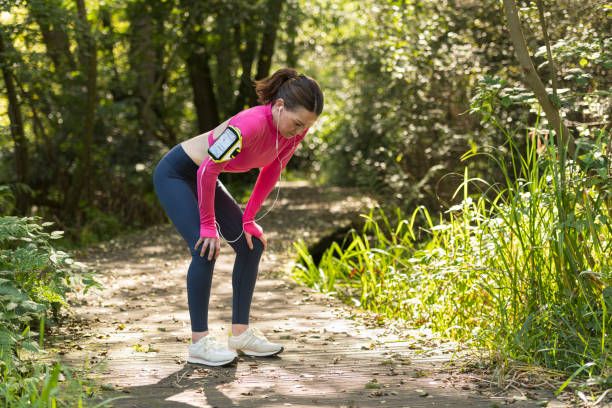 istock Sporty woman runner with her hands on her knees resting after exercise outdoors. Catching her breath. 2174689874