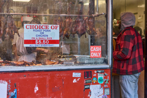 New York, United States -September 26,2024:  Window of a Chinese restaurant in New York, displaying roasted ducks and chickens with visible prices and an active cooking environment.