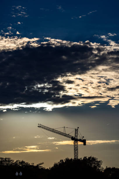 istock The tower crane on sunset sky. Industrial construction equipment. Tower Cranes. Construction site. Construction of Skyscrapers. Tower Crane on formworks. Crane and building construction. Cranes on Housing. 2174691226
