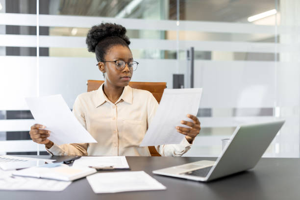istock Focused African American businesswoman reviewing documents in modern office while working diligently at desk 2174692363