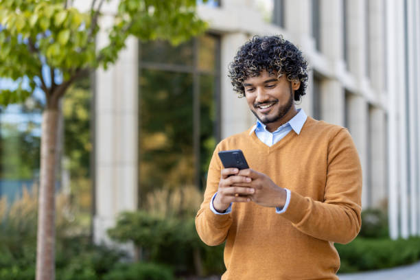 istock Smiling young professional using smartphone outdoors near modern office building in autumn 2174693631