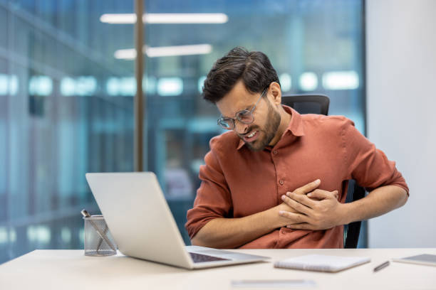 istock Businessman experiences chest pain while working at desk in modern office setting, indicating health issues during work hours 2174699024