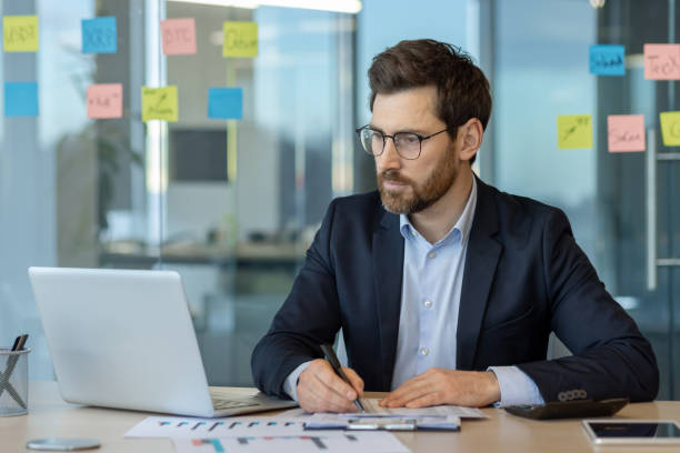 istock Focused businessman working on laptop in modern office setting 2174700419