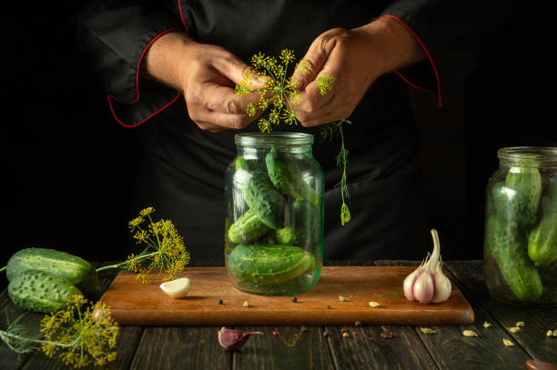 istock Preserving cucumbers in a jar by the cook hands for long-term storage. Adding dill to pickled vegetables 2174706757