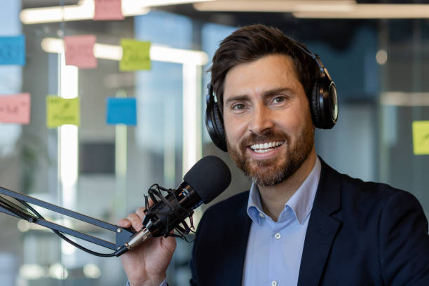 istock Confident podcast host wearing headphones while recording in office studio with microphone setup and sticky notes in background for creative inspiration 2174710496