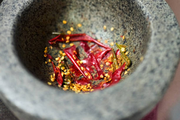Top view of dried and crushed red chili pepper in stone mortar on kitchen counter
