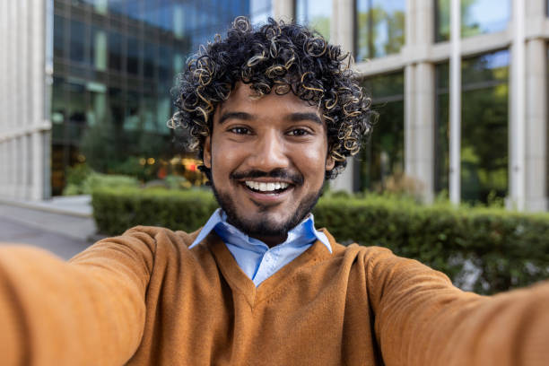 istock Confident young man taking selfie outdoors in business district, capturing cheerful expression on phone for video call 2174721974