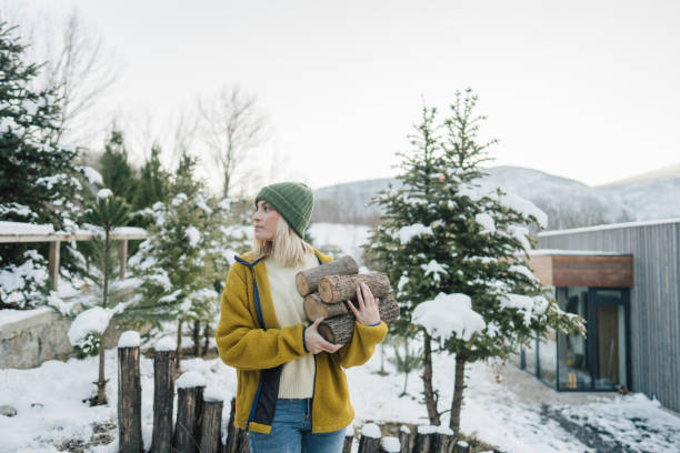 Photo of a young woman bringing chopped firewood into the house