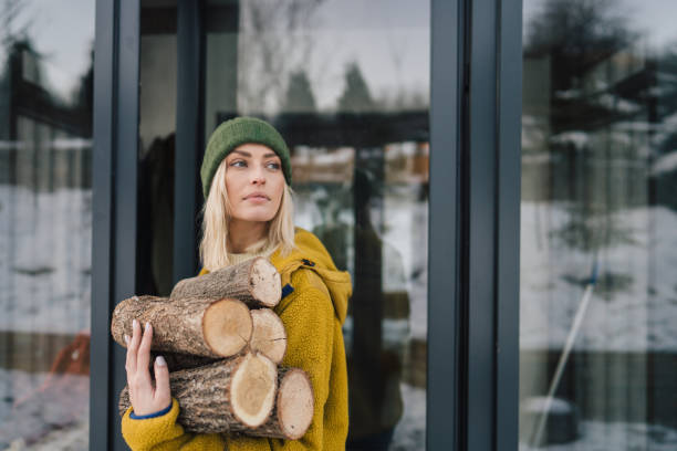 Photo of a young woman bringing chopped firewood into the house