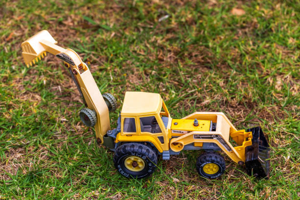 Whangamata, New Zealand - December 25, 2023: Vintage Yellow Toy Excavator on Grass in Backyard