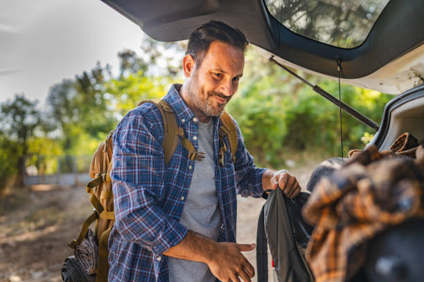istock Adult man take backpack from trunk ready for adventure in the forest 2174730885