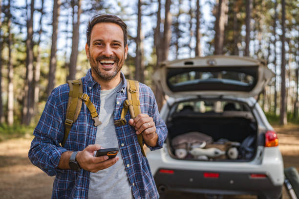 istock adult man camper use mobile phone in front car in the forest 2174731409