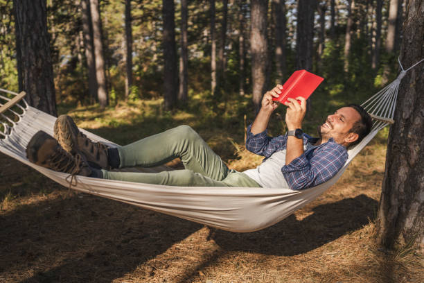 istock Adult man lying down and read book in hammock 2174731782
