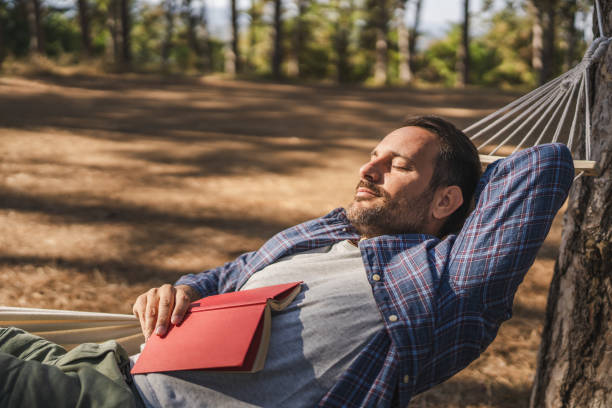 istock Adult man lying down and take a nap after read book in hammock 2174731827