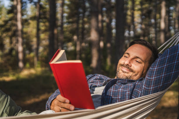 istock Adult man lying down and read book in hammock 2174731864