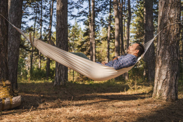 Adult man camper practice meditation and breath exercise in hammock