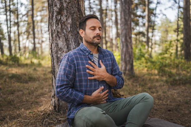 Adult man camper practice meditation and breath exercise in front tree