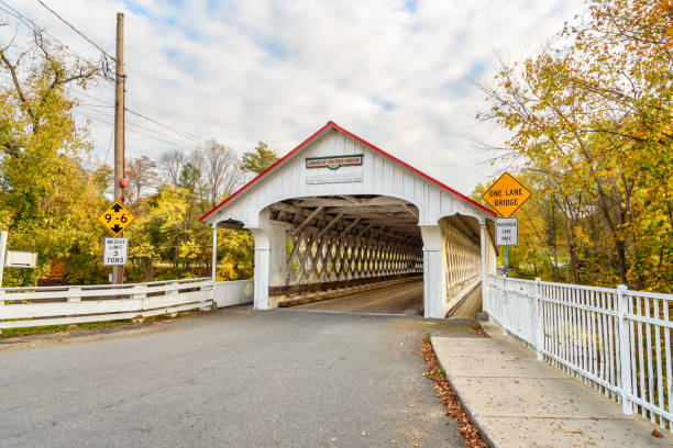 istock Traditional white covered bridge over a river on a partly cloudy fall day 2174734300