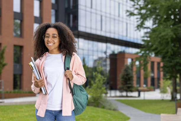 istock Confident african american student holding books outdoors on college campus with modern building in background 2174736005