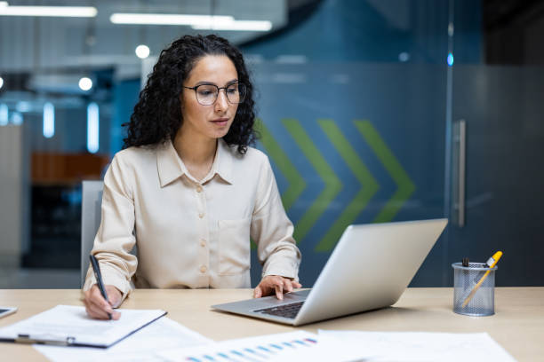 istock Hispanic accountant working seriously on a laptop in a modern office setting with focused expression while reviewing financial documents 2174736139