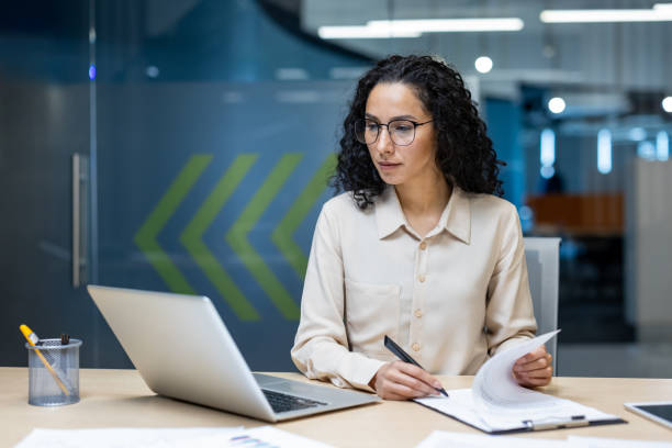 istock Serious Hispanic female accountant focuses on financial paperwork while working at modern office desk 2174739862
