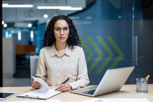 istock Confident Hispanic businesswoman working in modern office with laptop and documents, showcasing focus and professionalism 2174740710