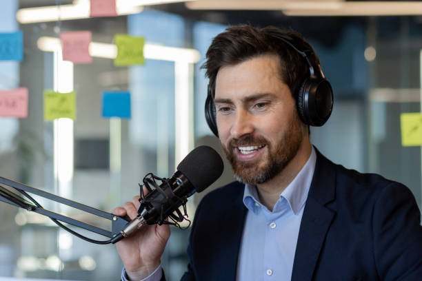 istock Confident man in office setting with headphones and microphone hosting podcast or online event, showcasing modern communication technology 2174741545