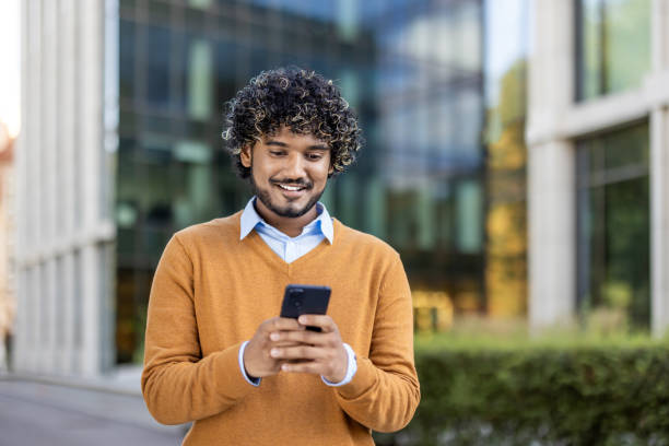 istock Young professional smiling while using smartphone outdoors in urban setting, wearing casual attire and enjoying modern technology during break 2174746980