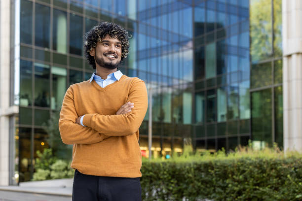 istock Confident young professional standing outside modern office building with arms crossed and optimistic expression 2174747521