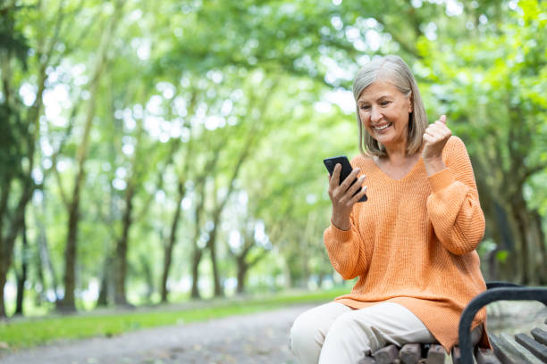 istock Elderly woman smiling while using smartphone outdoors enjoying modern technology in peaceful park setting 2174751448