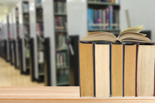 istock Library Background. Book stack in library on the wooden table. blurred bookshelf background 2174753966