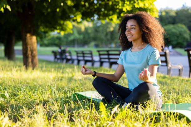 istock Woman meditating outdoors on sunny day in park, practicing mindfulness and relaxation surrounded by nature 2174754038