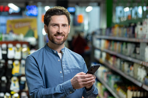 istock Smiling man using smartphone in grocery store aisle surrounded by products and shelves, showcasing online shopping or digital communication lifestyle 2174754670